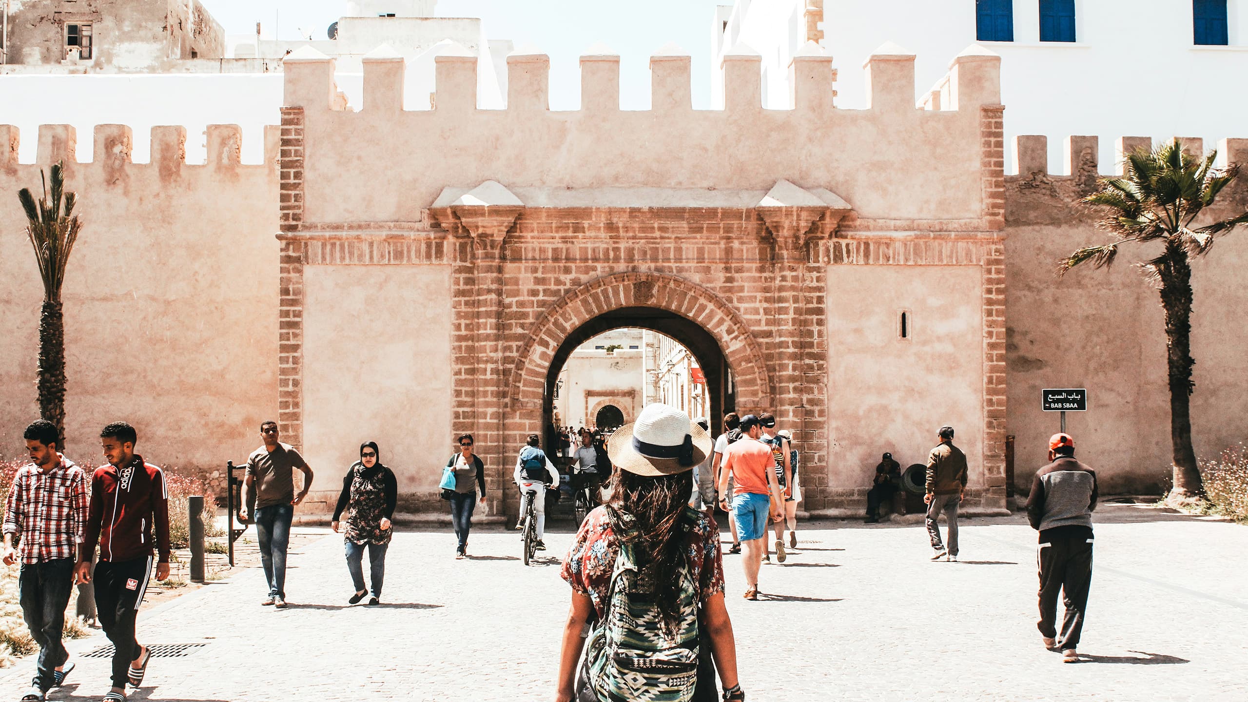 Frau mit Hut und Rucksack vor einem massiven Steintour in Essaouira